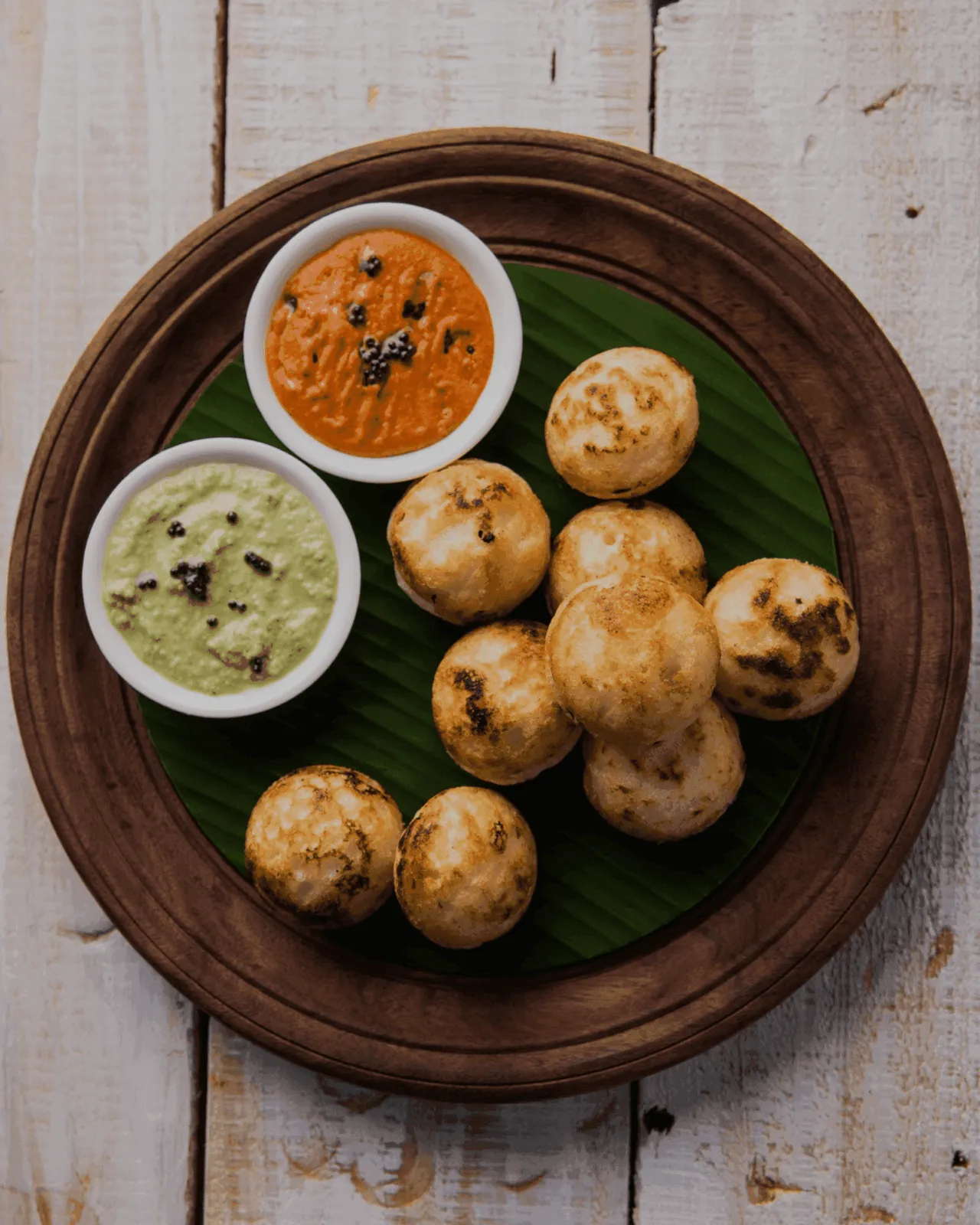 Roasted Litti served on a banana leaf with red and green chokha chutneys