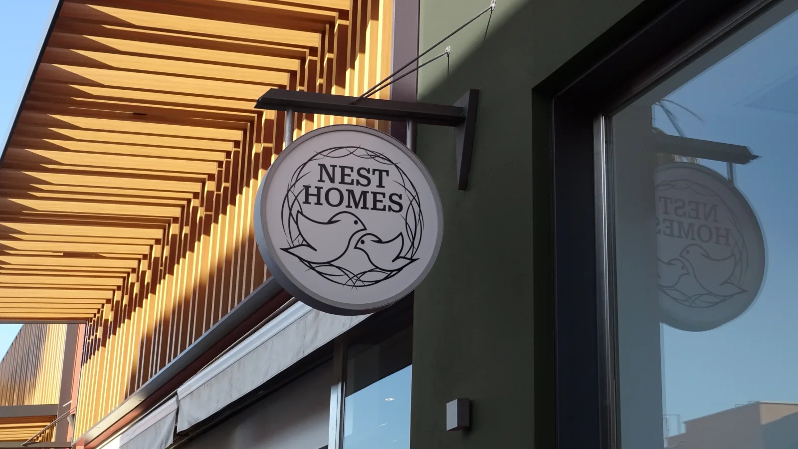 Nest Homes circular hanging wooden storefront signage mockup